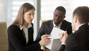 A woman speaks to two men and a woman in a business meeting